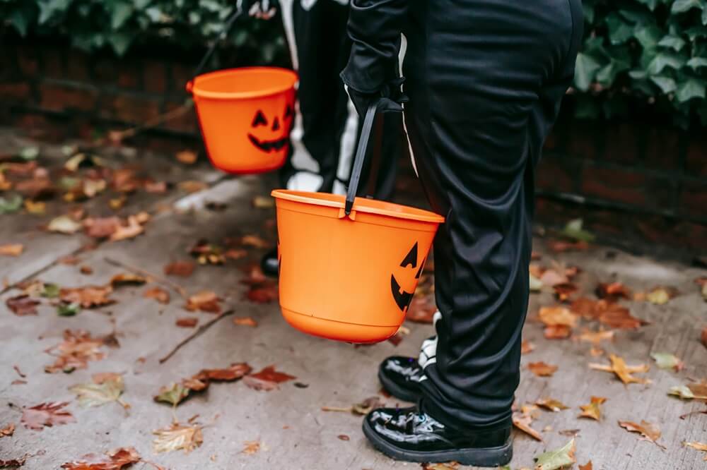 children trick or treating on a concrete sidewalk